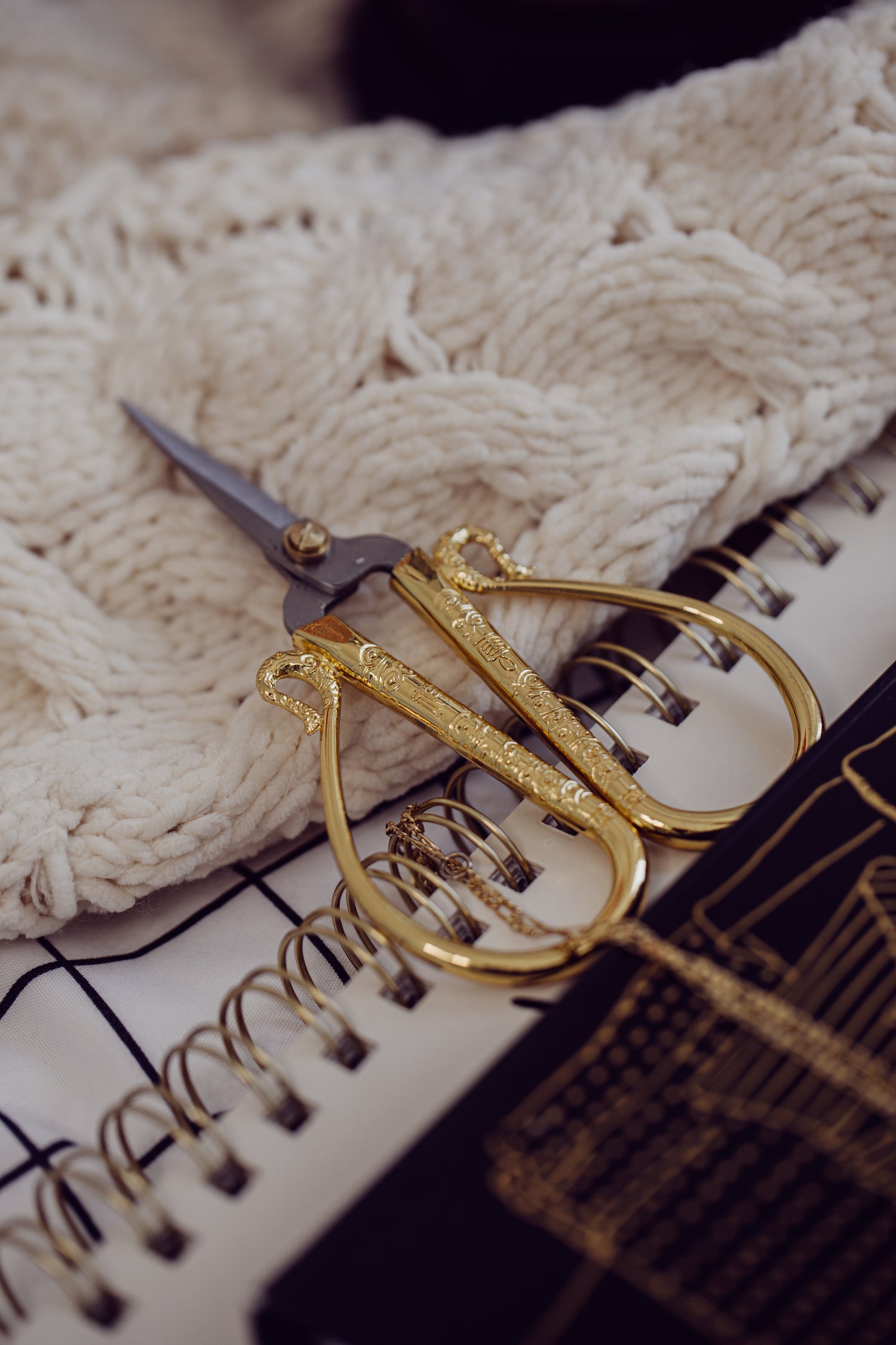 Elegant golden crafting scissors resting on a notebook next to soft fabric, illustrating Step 1 The Anchor of Deeds for the MyyaTales Chronicle.