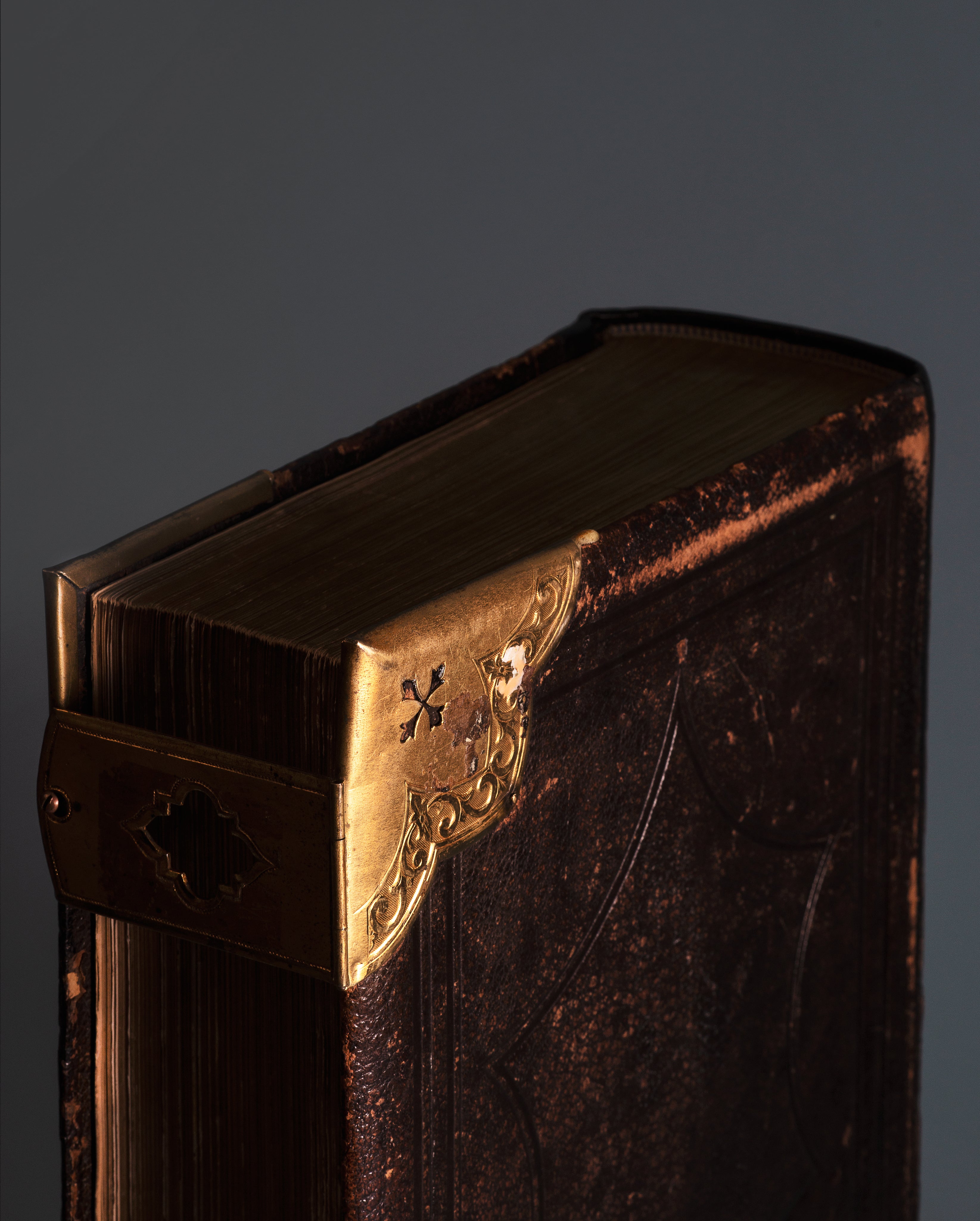 Close-up of the ornate brass corners on an antique leatherbound book, acting as a background banner for the Secret Scrolls section by MyyaTales.